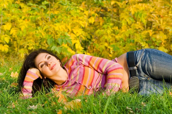 Junge hübsche Frau ruht auf dem herbstlichen Gras — Stockfoto