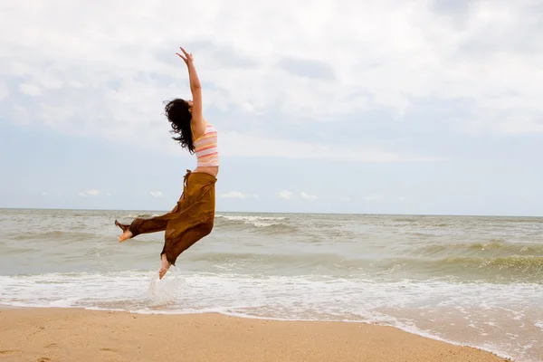 행복 한 젊은 여성이 해변에서 점프 — 스톡 사진