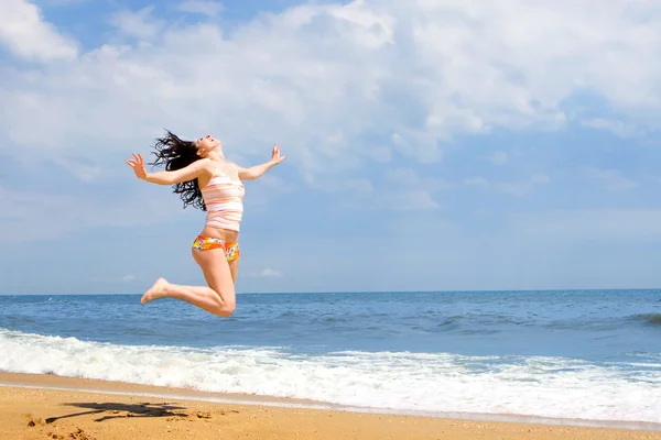 Ausdrucksstarke junge Frau springt in den Strand — Stockfoto