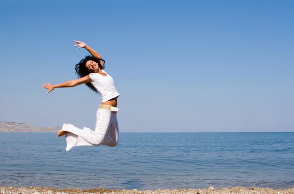 Szczęśliwa młoda kobieta jest skakanie na plaży — Zdjęcie stockowe