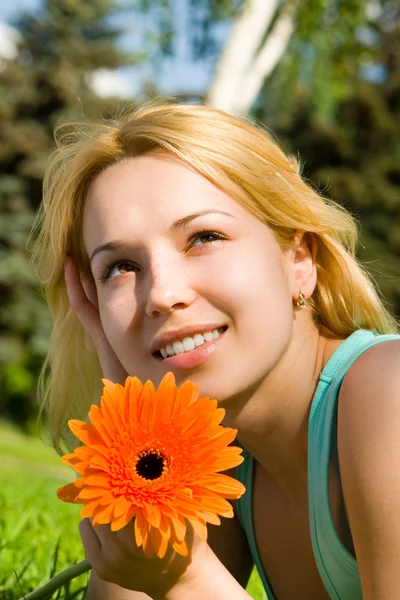 Hübsche Frau ruht sich im Park mit Blumen aus — Stockfoto