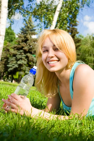 Ładna kobieta wody pitnej na polanie lato — Zdjęcie stockowe