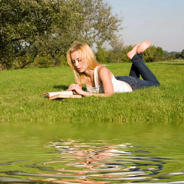Молодая блондинка читает книгу в парке — стоковое фото