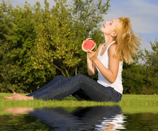 Junge Blondine isst Wassermelone im Park — Stockfoto