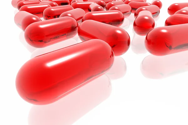 Червоні таблетки на білому тлі — стокове фото
