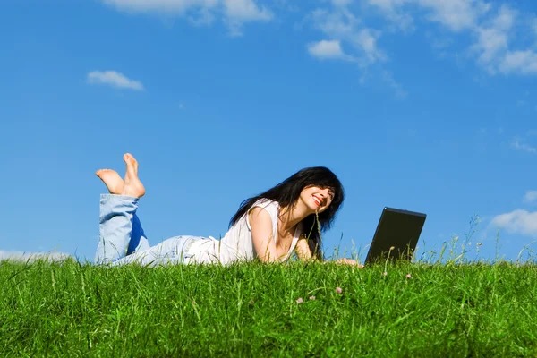 Pretty woman with laptop on the green grass Stock Picture