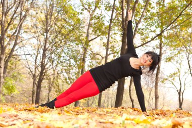 güzel bir kadın yoga egzersizleri sonbahar Park yapıyor