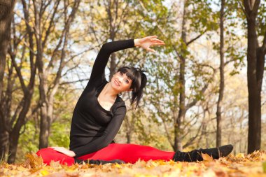 güzel bir kadın yoga egzersizleri sonbahar Park yapıyor