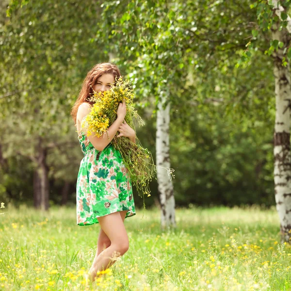 Молодая рыжая женщина в парке с цветами — стоковое фото