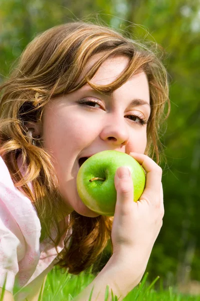 Güzel bir kadın yaz glade üzerinde yeşil elma yiyen — Stok fotoğraf