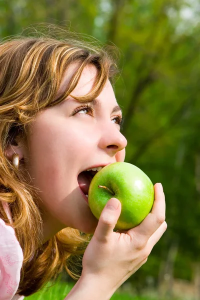 Vacker kvinna äta grönt äpple på sommaren gläntan — Stockfoto