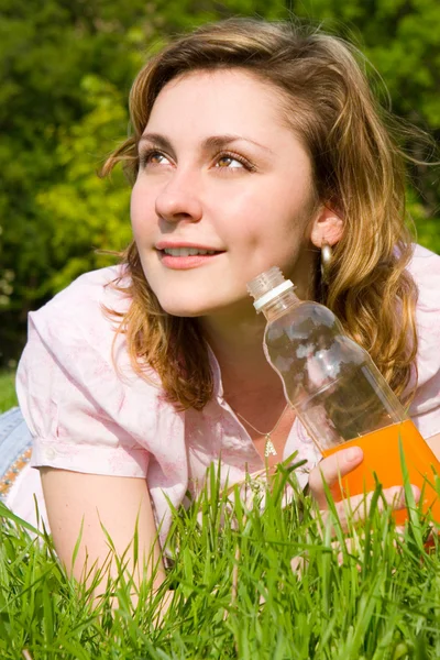 Yeşil çimenlerin üzerinde suyu içme kadın — Stok fotoğraf