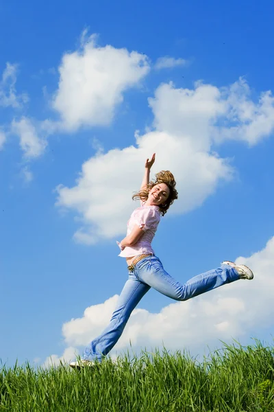 Счастливая молодая женщина прыгает в зеленую траву — стоковое фото