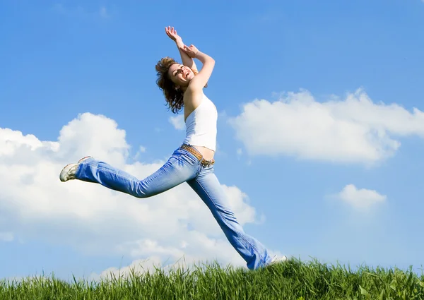 Счастливая молодая женщина прыгает в зеленую траву — стоковое фото