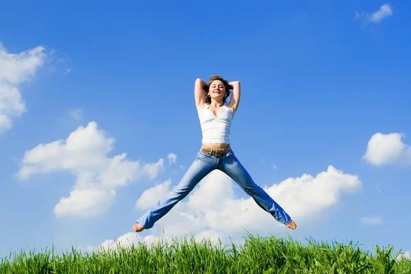 Mutlu genç kadın yeşil otların arasında atlama — Stok fotoğraf