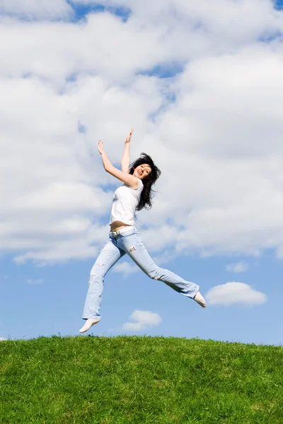 年轻漂亮的女人在绿草地上跳跃 — 图库照片