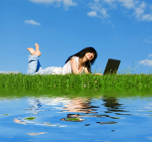 Jolie femme avec ordinateur portable sur l'herbe verte — Photo