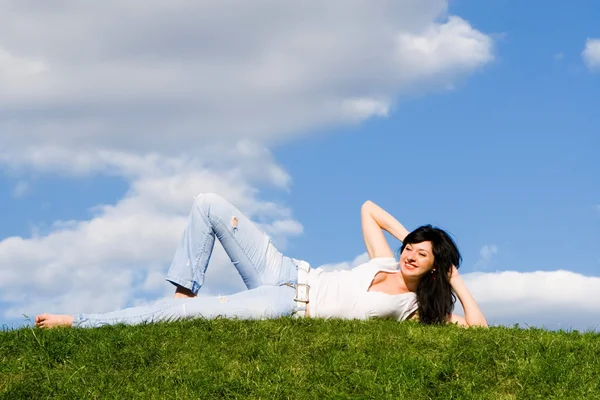 Mooie vrouw rust op het groene gras — Stockfoto