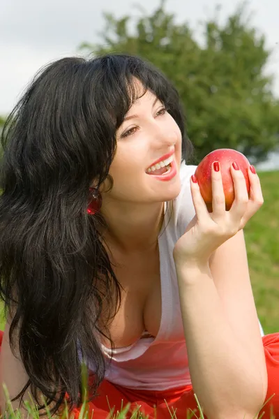 Bella donna mangiare mela rossa sulla radura estiva — Foto Stock