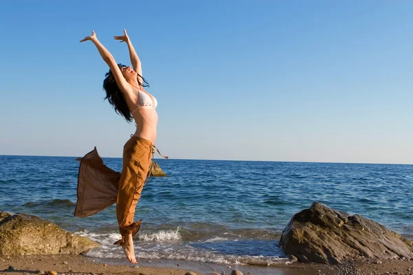 Fröhliche junge Frau tanzt am Strand — Stockfoto