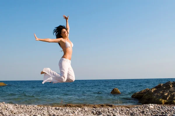 행복 한 젊은 여성이 해변에서 점프 — 스톡 사진