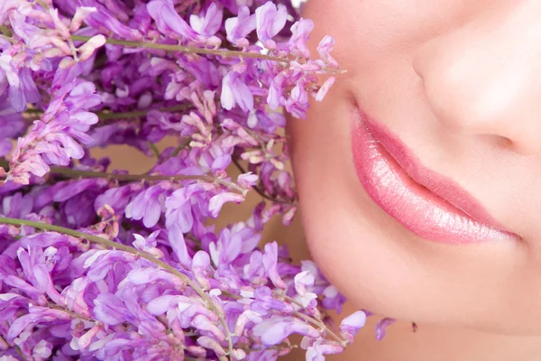 Et smil fra en ung kvinne med blomster – stockfoto