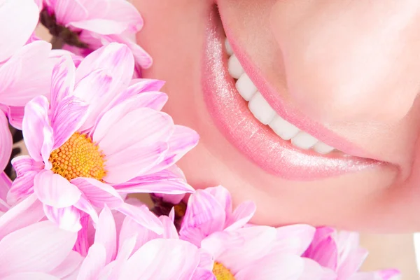 Et smil fra en ung kvinne med blomster – stockfoto