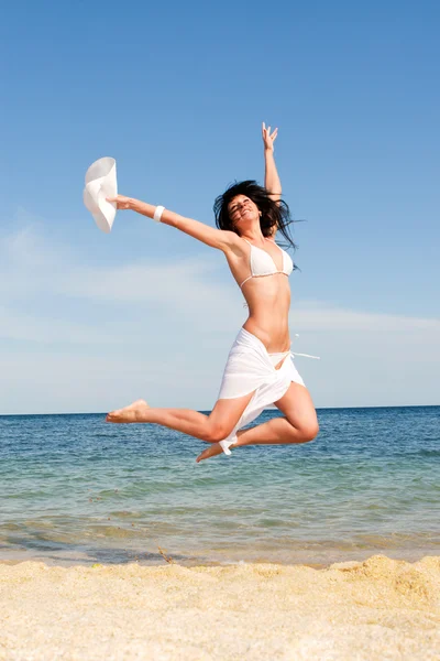 Glückliche junge Frau springt in den Strand — Stockfoto