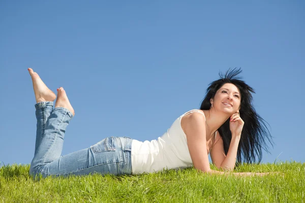 Gelukkig jonge vrouw rust op het groene gras — Stockfoto