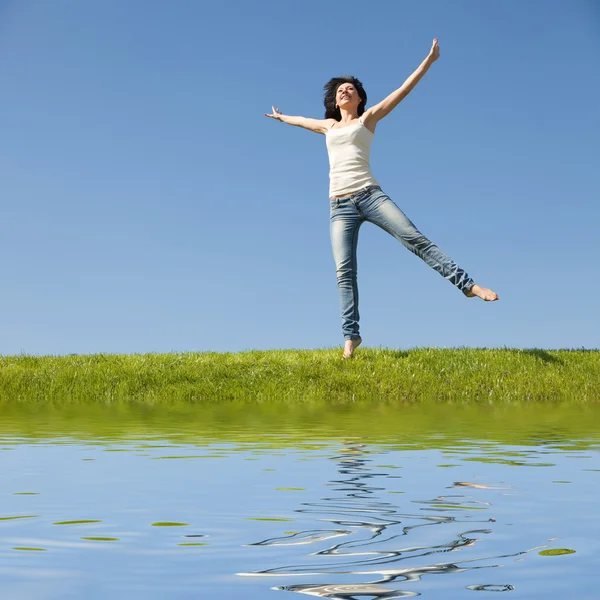 Bardzo młoda kobieta, skoki na zielonej trawie — Zdjęcie stockowe