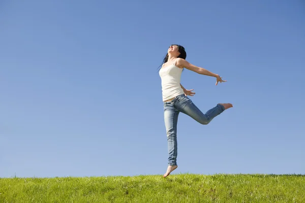 Ganska ung kvinna hoppa på grönt gräs — Stockfoto
