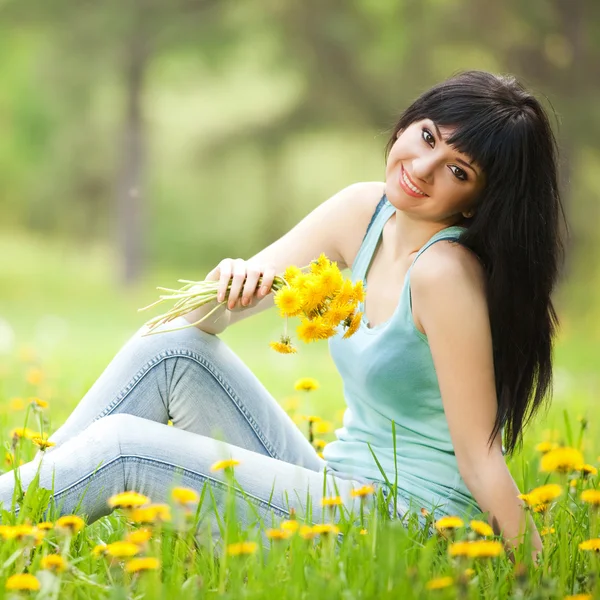 Cute woman in the park with dandelions — Zdjęcie stockowe