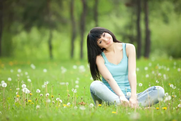 Cute woman in the park with dandelions — Stock Photo, Image
