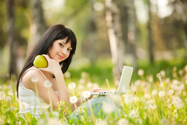 민들레와 함께 공원에서 흰색 노트북으로 귀여운 여자 — 스톡 사진