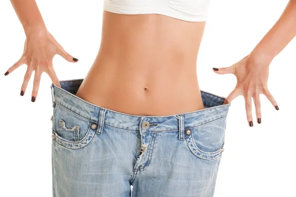Funny woman shows her weight loss by wearing an old jeans — Stock Photo, Image