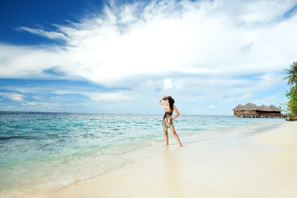 Mujer tranquila en la playa tropical con bungalows —  Fotos de Stock