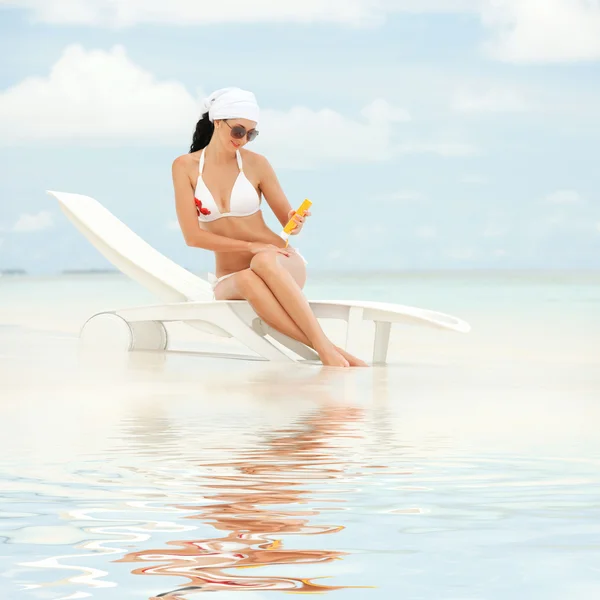 Jonge vrouw met bescherming tegen de zon crème op het strand — Stockfoto