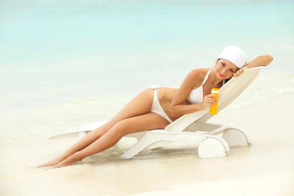 Jeune femme avec crème solaire sur la plage — Photo