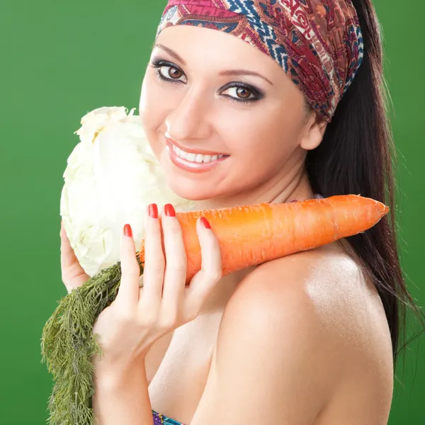 Menina bonita com cenoura e repolho no fundo verde — Fotografia de Stock