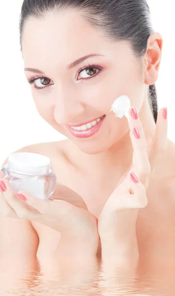 Mujer aplicando crema en su cara sobre el fondo blanco —  Fotos de Stock