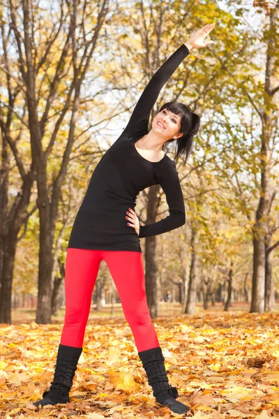 Pretty woman doing yoga exercises in the autumn park — Stock Photo, Image