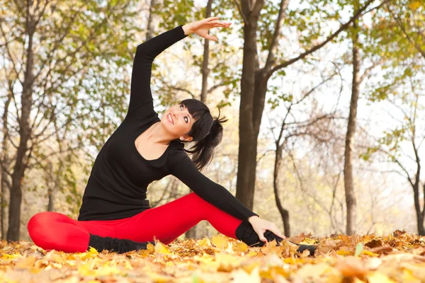 Mujer bonita haciendo ejercicios de yoga en el parque de otoño —  Fotos de Stock