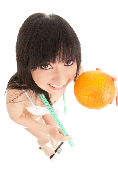 Fun woman with orange and measure tape on the glass scales — Stock Photo, Image