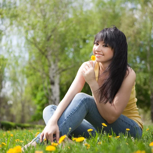 Niedliche Frau im Park mit Löwenzahn — Stockfoto