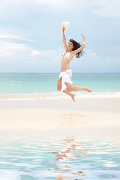 Joyeux jeune femme sautant sur la plage — Photo