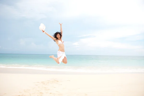 Glückliche junge Frau springt in den Strand — Stockfoto