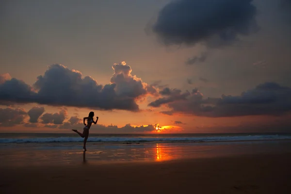 Ενεργητική και δραστήρια γυναίκα που τρέχει σε ένα ηλιοβασίλεμα στην παραλία — Φωτογραφία Αρχείου