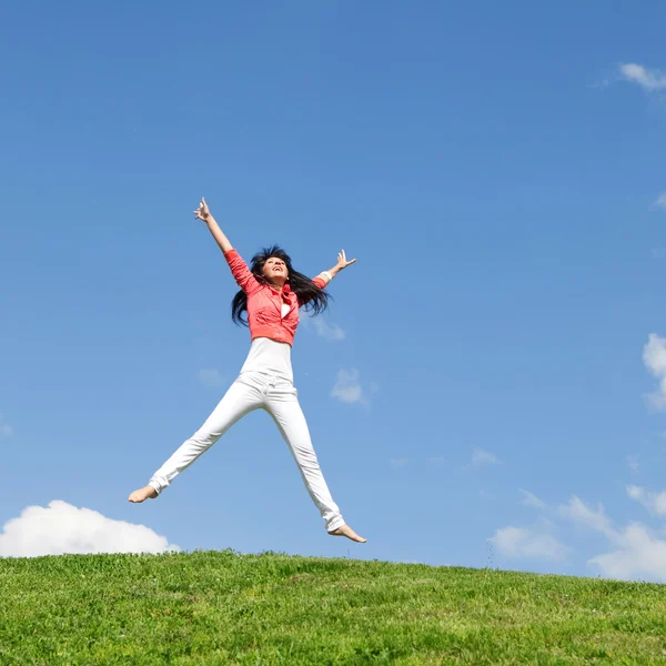 Mooie jonge vrouw springen op groen gras — Stockfoto