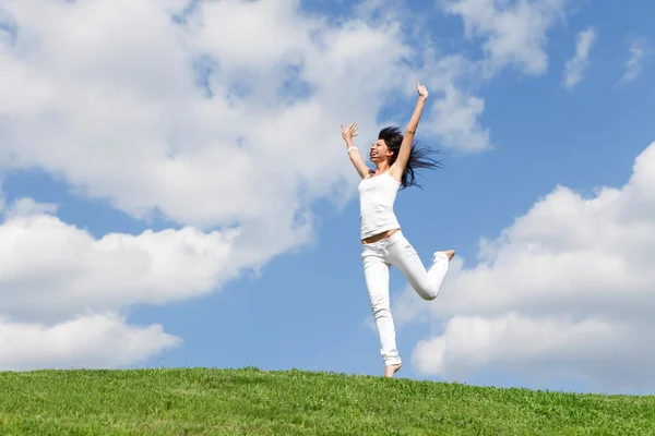 Красива молода жінка стрибає на зеленій траві — стокове фото