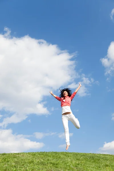 Красивая молодая женщина прыгает на зеленой траве — стоковое фото